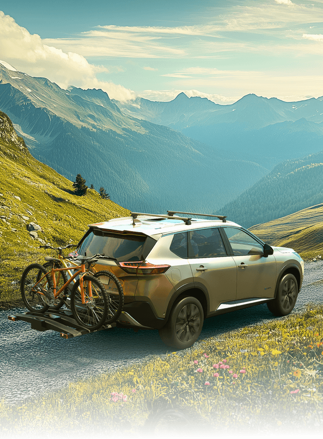 Nissan X-Trail mit beladenem Fahrradträger fährt durch eine farbenfrohe Frühlingslandschaft.